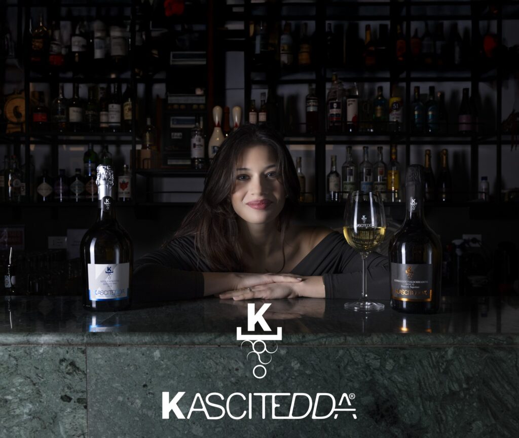 Modella al bancone de IL CLUB Siracusa con le bottiglie di Prosecco Kascitedda e il logo del marchio